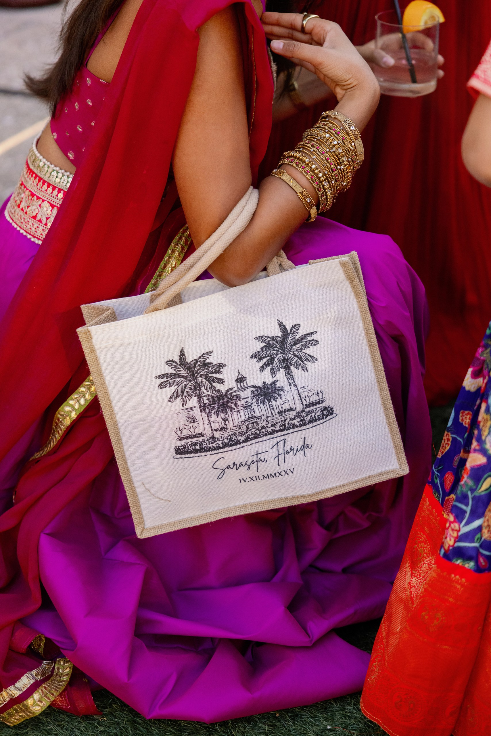 guest at sangeet in Sarasota, Florida holding a canvas tote that is customized with a sketch of the Ritz Carlton Sarasota and the couples wedding date.
