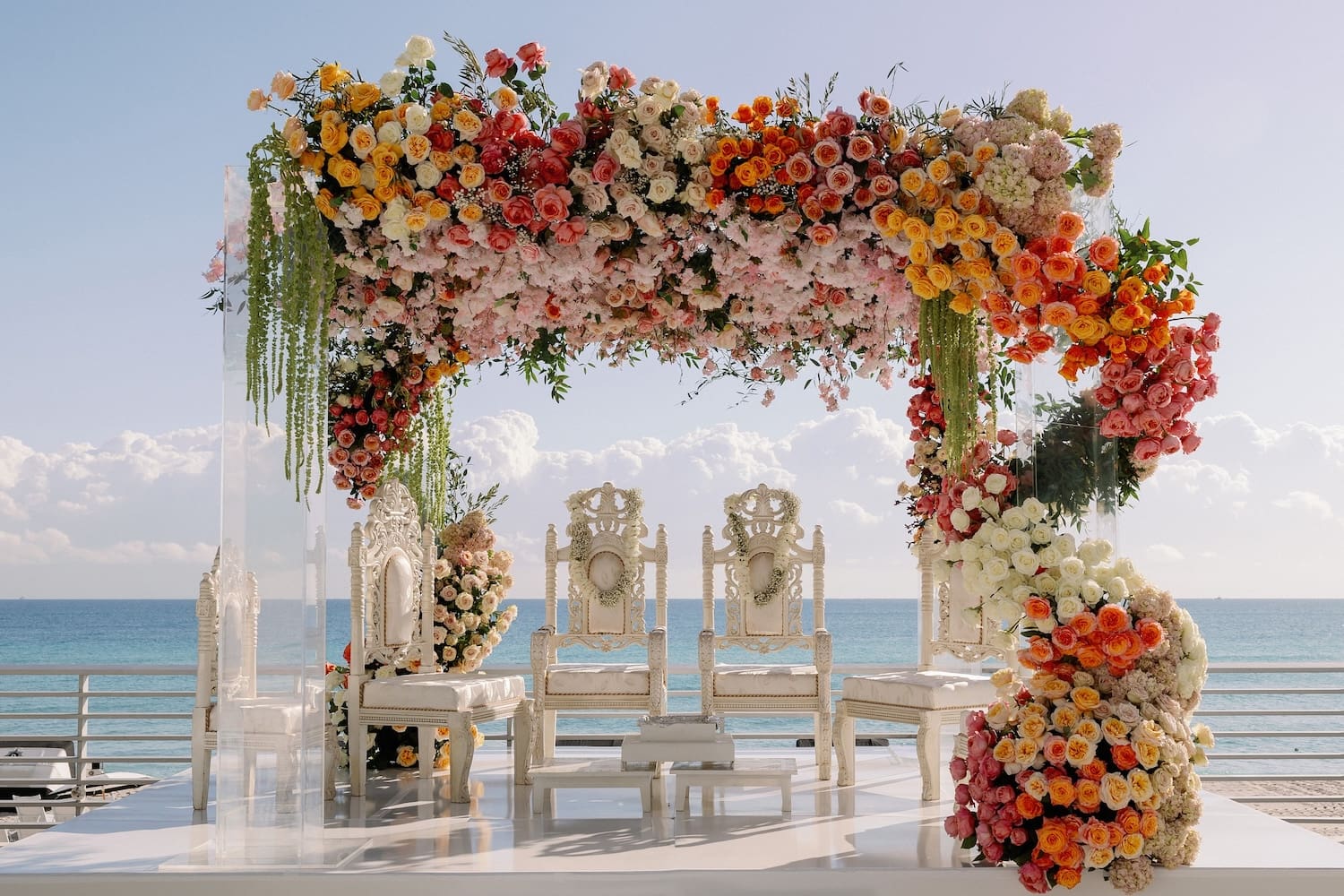 ombre colorful floral mandap on beach with ocean in background